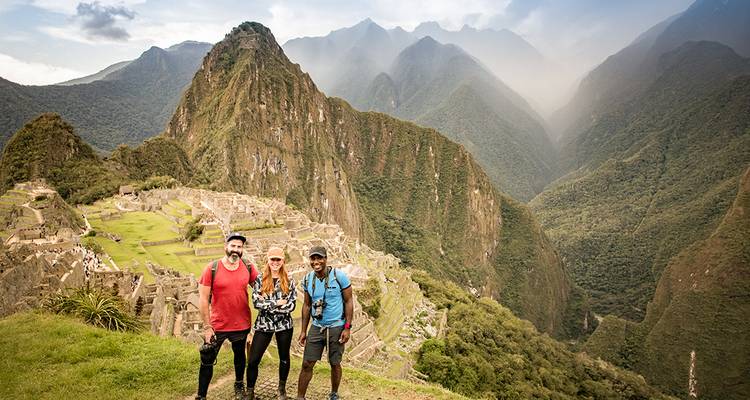 Tres excursionistas posando con Machu Picchu de fondo.