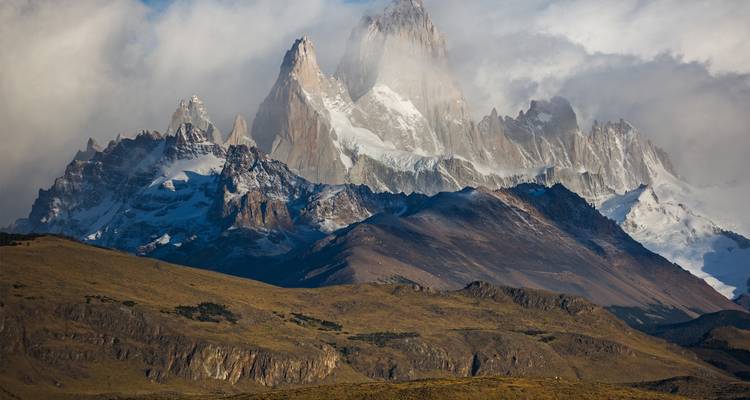 Pics montagneux majestueux partiellement couverts par les nuages.