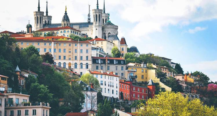 Bâtiments colorés sur une colline avec la Basilique Notre-Dame de Fourvière au sommet.