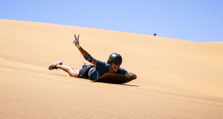 Persona haciendo sandboard por una duna.