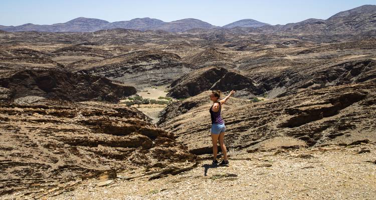 Persona señalando mientras está de pie en un paisaje rocoso.