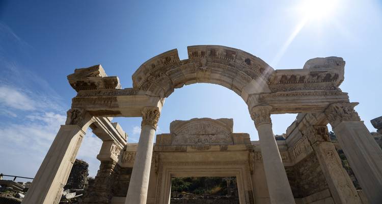 Arco de piedra antiguo con tallas ornamentales bajo un cielo azul despejado.