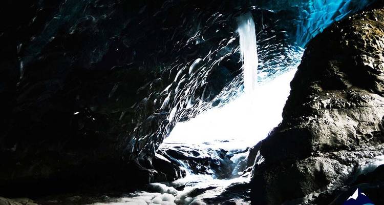 Entrada a una cueva de hielo con luz azul filtrándose a través del hielo.