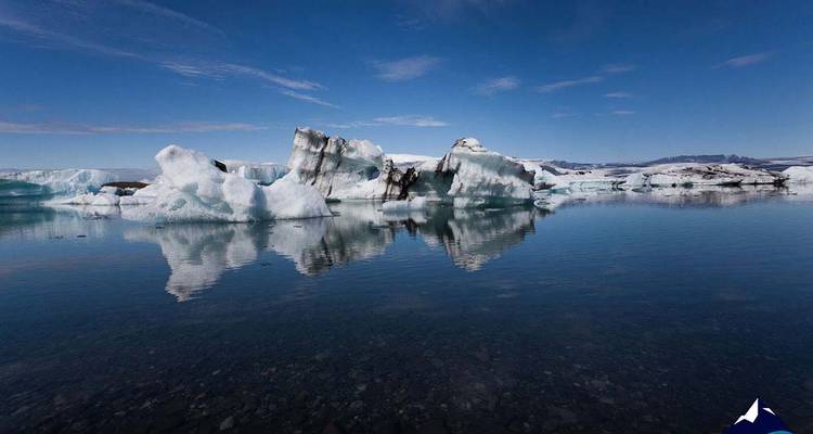 Icebergs flotando en un lago tranquilo bajo un cielo despejado.