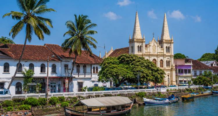 Colonial waterfront of Kochi with white-washed Portuguese buildings, twin-spired basilica and tall palm trees.
