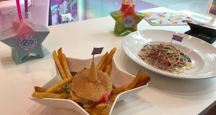 Une table avec un burger, des frites, des boissons colorées et des pâtes.
