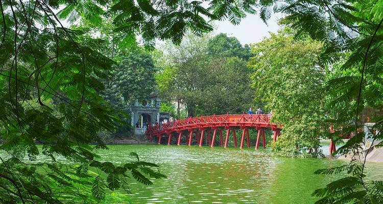 El Puente Huc sobre un lago verde rodeado de árboles en Hanoi.