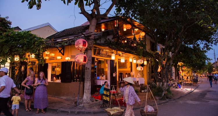 Escena callejera con tiendas y faroles al anochecer en Hoi An, Vietnam.
