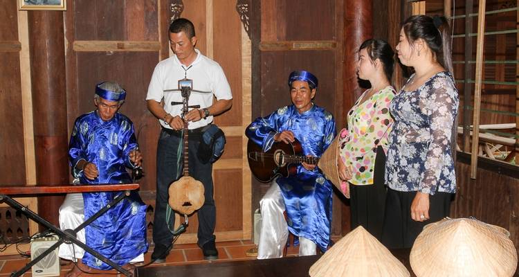Grupo de músicos y espectadores dentro de una habitación tradicional de madera.