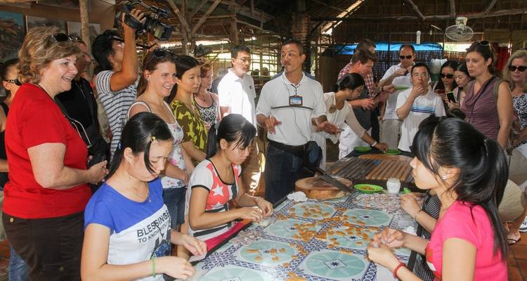 Los turistas se reunieron alrededor de una mesa haciendo dulces en un entorno tradicional.