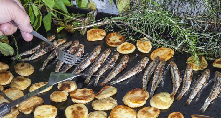Gegrilde vis en aardappelen op de barbecue met kruiden.