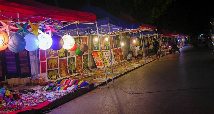 Mercado nocturno con luces coloridas y diversos productos.