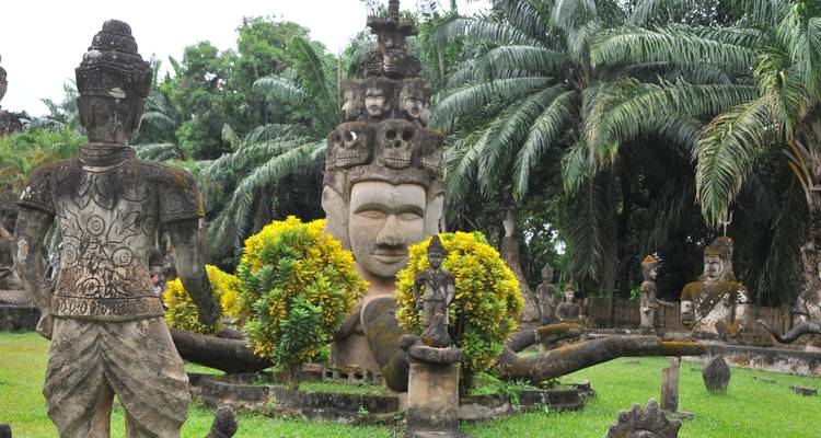 Estatuas antiguas en un jardín exuberante.
