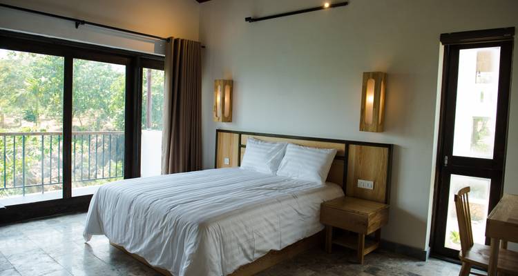 Interior de habitación de hotel con una cama bien tendida y vista a la ventana.