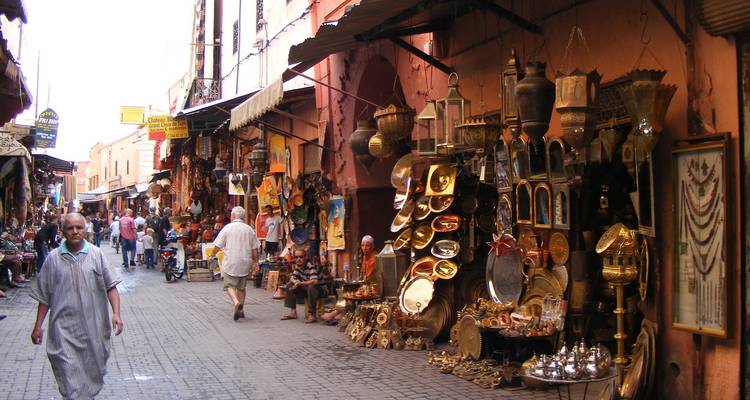 Un marché de rue avec des produits traditionnels devant des bâtiments rustiques.