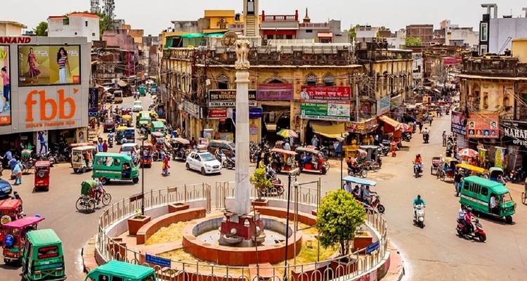 Place de ville animée avec circulation et magasins.