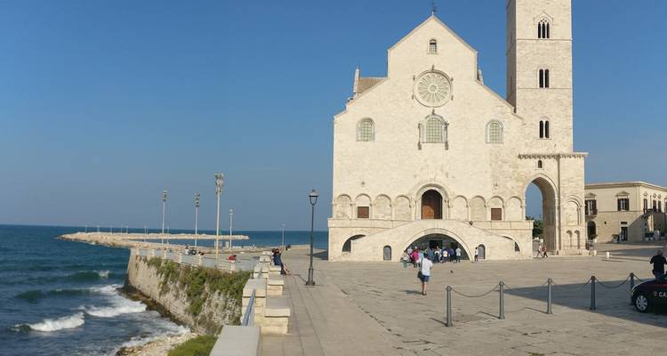 Eine Küstenkathedrale mit Menschen, die entlang der Uferpromenade spazieren gehen.
