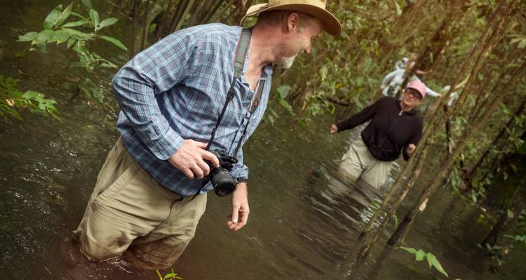 Les voyageurs pataugeant jusqu'à la taille dans la forêt amazonienne inondée lors d'une excursion animalière aventureuse