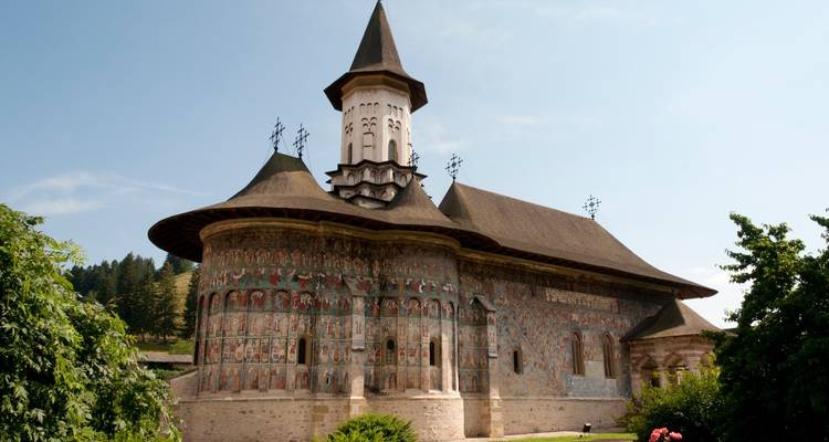 Mur extérieur peint d'une église historique avec des fresques religieuses.