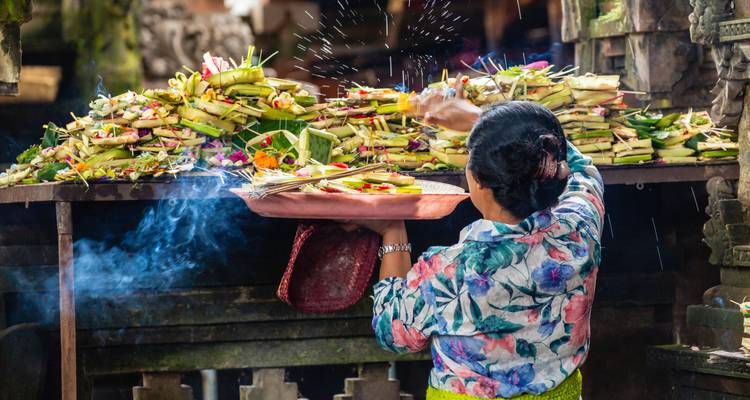 Balinese vrouw die kleurrijke tempeloffers op een rokerig altaar voorbereidt