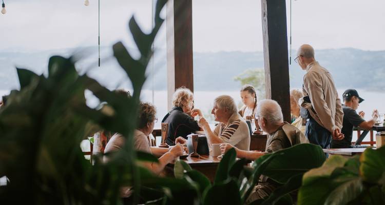 Reisende, die sich an einem von üppigen Zimmerpflanzen umrahmten Restauranttisch unterhalten.