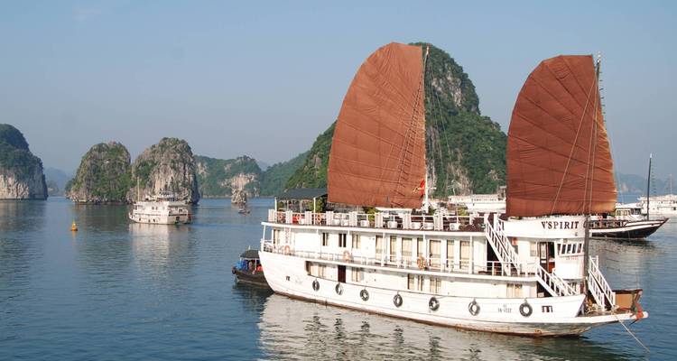 Traditional Vietnamese boat with red sails navigating through Halong Bay.