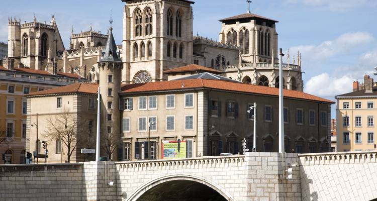 Cathédrale gothique iconique et pont au-dessus d'une rivière dans un paysage urbain.