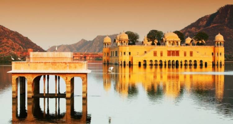 El palacio Jal Mahal en medio de un lago al atardecer.