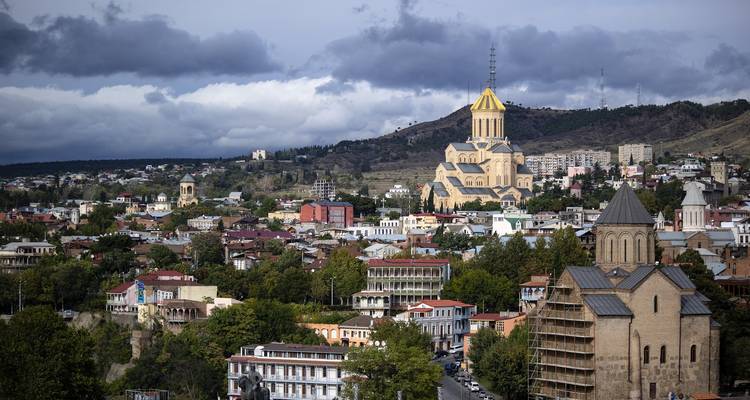 Cityscape of Tbilisi with historic churches and modern buildings.