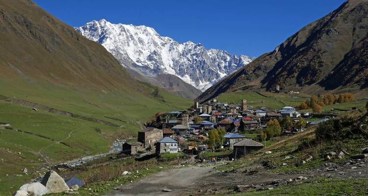 Village nestled in a valley with snow-capped mountains in Ushguli.
