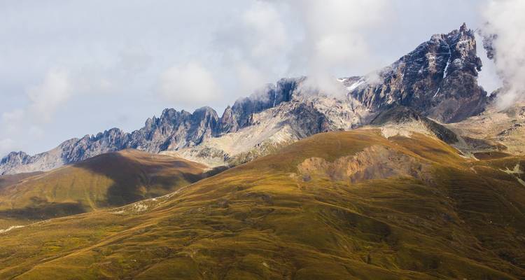 Majestic mountain peaks with clouds and golden sunlight.