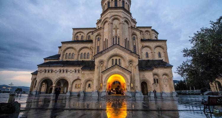 Large church illuminated in the evening with people gathering around.