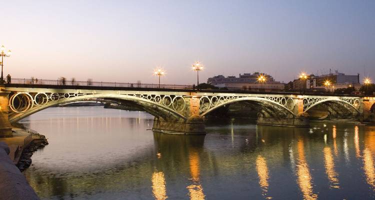 Pont orné enjambant une rivière au coucher du soleil.