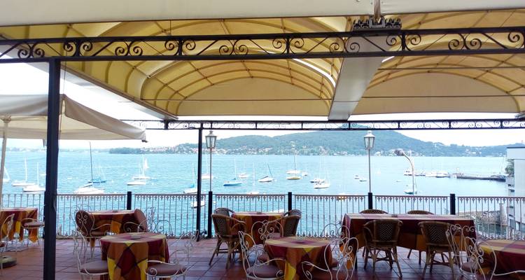 Terraza de café al aire libre con vista al lago y veleros.