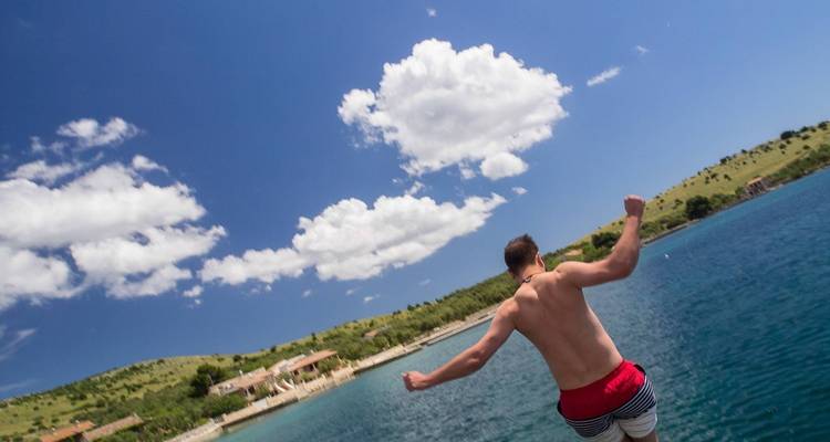 Hombre saltando al agua con un cielo azul claro.