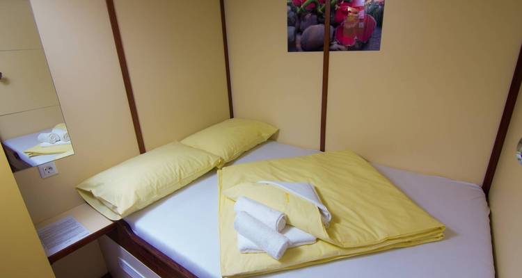 Interior de una habitación con una cama bien tendida y ropa de cama amarilla.