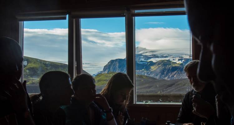 Silhouetted group indoors looking out at a scenic mountain view.