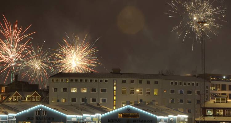 Feux d'artifice au-dessus des bâtiments d'une ville la nuit.