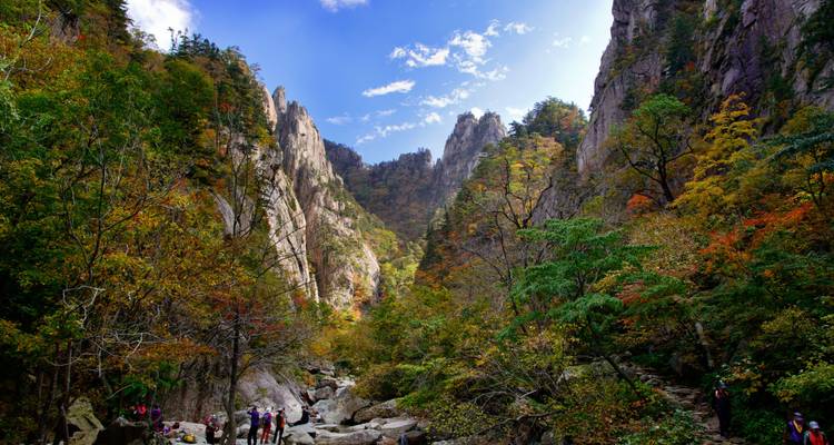 Les falaises de granit imposantes et le feuillage automnal dans un canyon spectaculaire du parc national de Seoraksan avec des randonneurs en contrebas.