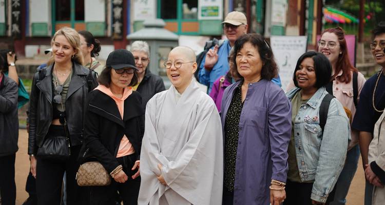 Les participants du circuit écoutent une religieuse bouddhiste lors d'une visite de temple.