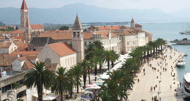 Promenade animée avec église historique et arbres par une journée ensoleillée.