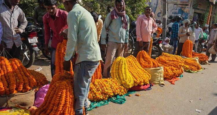 Street vendors arranging heaps of bright orange and yellow marigold garlands at a market