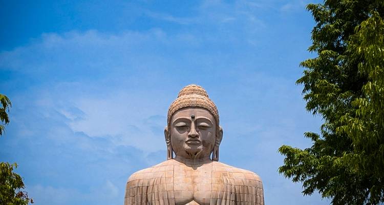 Partie supérieure de la statue monumentale de Bouddha se détachant sur un ciel dégagé.