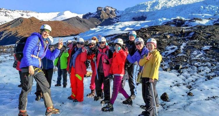 Gruppe von Touristen, die in Sicherheitsausrüstung auf einem Gletscher posieren.