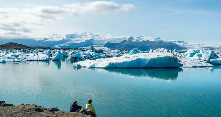 Eisberge, die in einer Gletscherlagune mit Bergen treiben