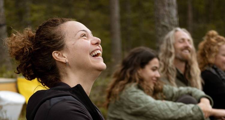 Group of people smiling and relaxing in a forest.