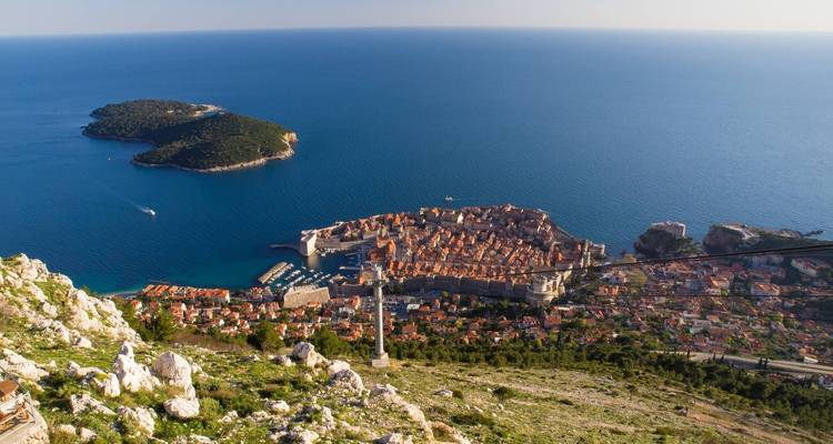 Vue aérienne de la vieille ville de Dubrovnik entourée de remparts, adjacente à la mer.