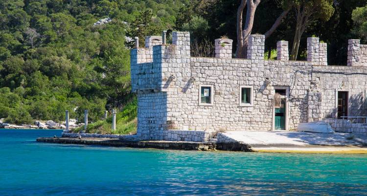 Bâtiment en pierre au bord de l'eau bleue entouré d'arbres sur l'île de Mljet.