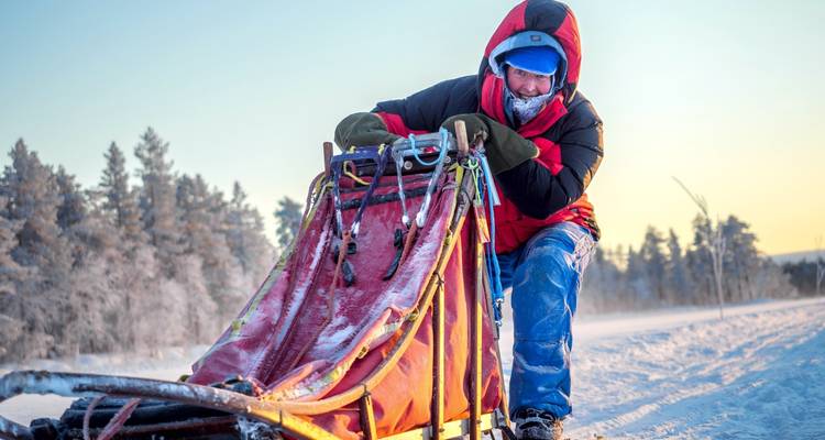 Persoon met een slee in een besneeuwd landschap.