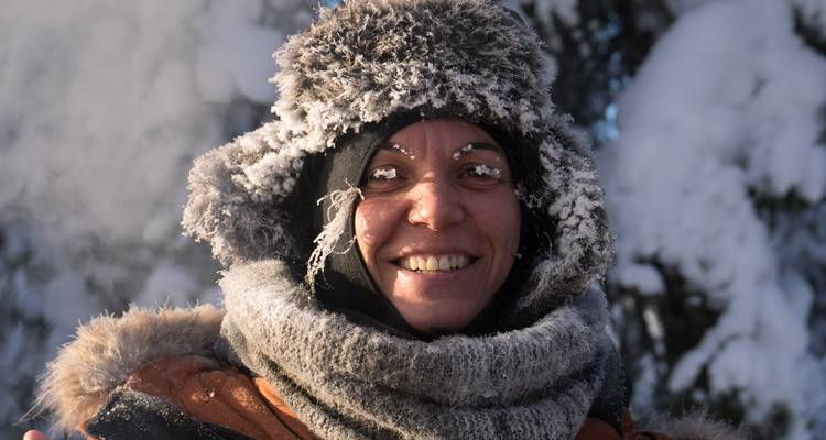 Glimlachende persoon in besneeuwde winterkleding.